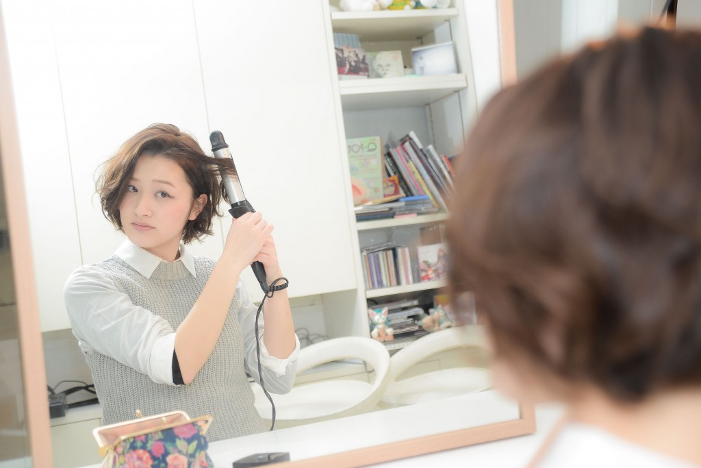 ヘアアイロンでカールするガール