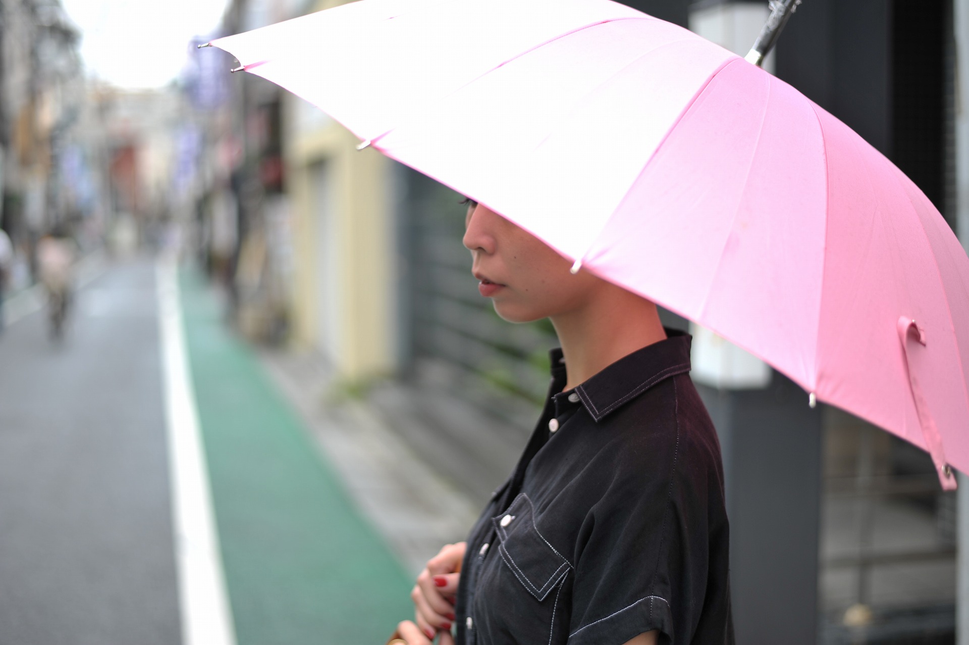 ピンク色の傘をさして雨をしのぐ